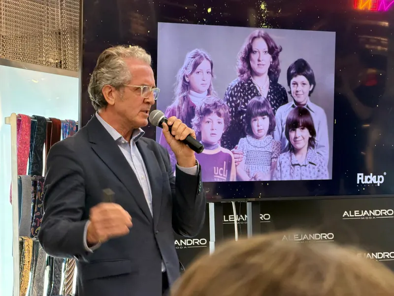Sergio Lara habla con micrófono en Fuckup Nights Zaragoza, con una foto familiar proyectada en la pantalla