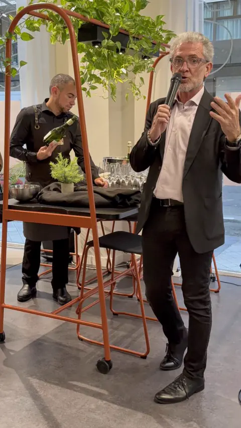 Un ponente habla con micrófono junto a la mesa de cata en el showroom de Lara