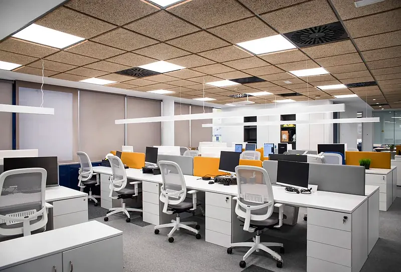 Zona de puestos de trabajo de la sede de Chint en Madrid, con mesas blancas, sillas operativas y techo acústico